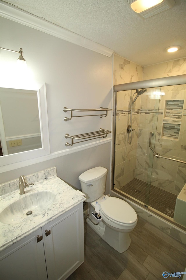 bathroom featuring a textured ceiling, wood-type flooring, a shower with shower door, and vanity