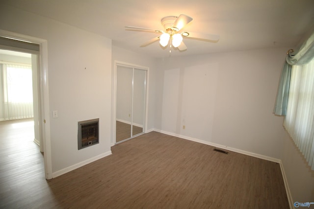 spare room featuring heating unit, dark hardwood / wood-style flooring, and ceiling fan