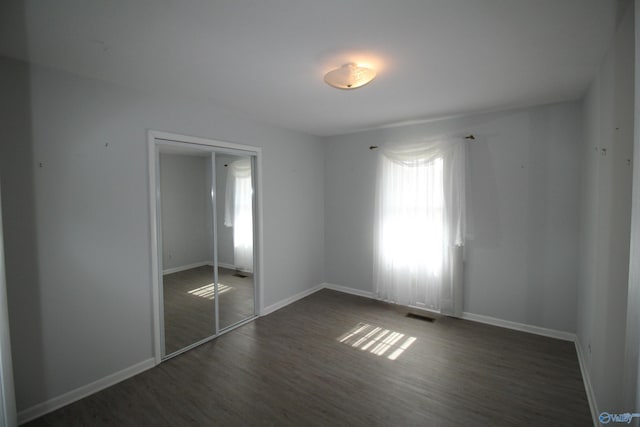 unfurnished bedroom with dark wood-type flooring and a closet