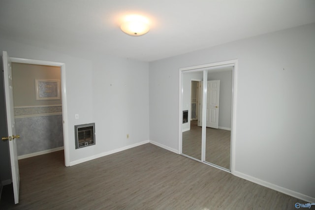 unfurnished living room featuring heating unit and dark wood-type flooring