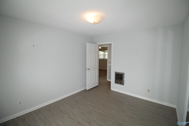 empty room with a fireplace, dark hardwood / wood-style flooring, and heating unit