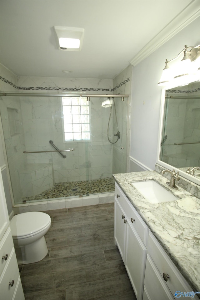 bathroom featuring hardwood / wood-style flooring, toilet, an enclosed shower, crown molding, and vanity