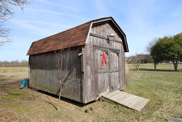 view of outdoor structure with a rural view and a lawn