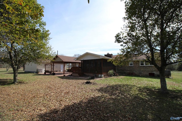 rear view of house featuring a yard and a sunroom