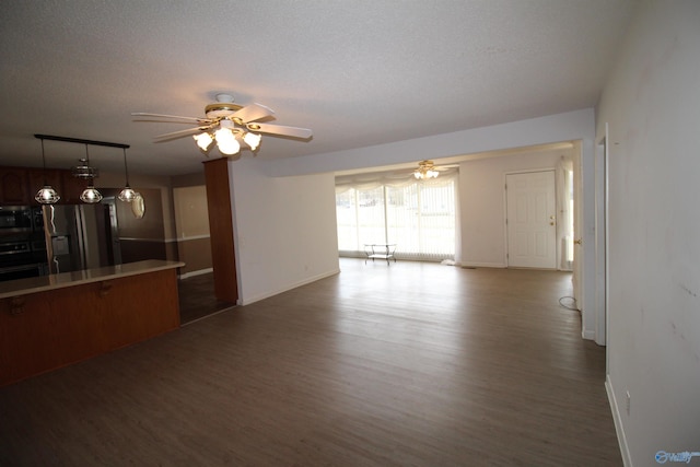 unfurnished living room with a textured ceiling, dark wood-type flooring, and ceiling fan