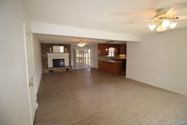 unfurnished living room with a brick fireplace, a textured ceiling, and hardwood / wood-style floors