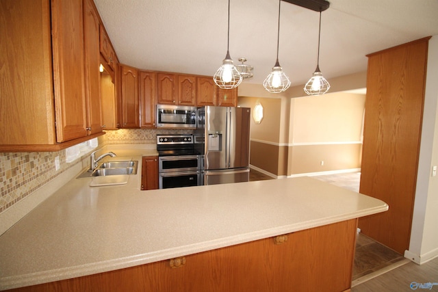 kitchen with sink, pendant lighting, stainless steel appliances, kitchen peninsula, and decorative backsplash