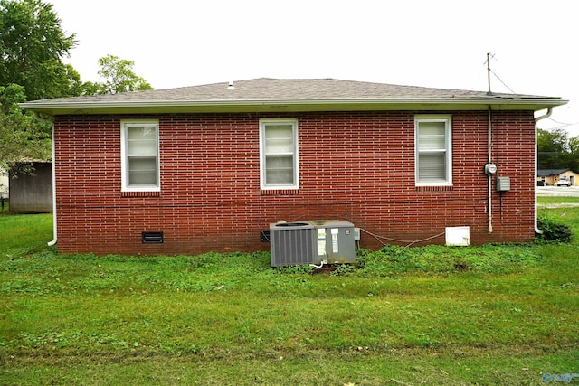 rear view of property featuring a lawn and central air condition unit