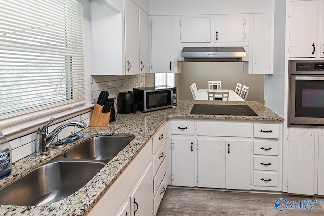 kitchen with appliances with stainless steel finishes, sink, white cabinets, and wall chimney exhaust hood