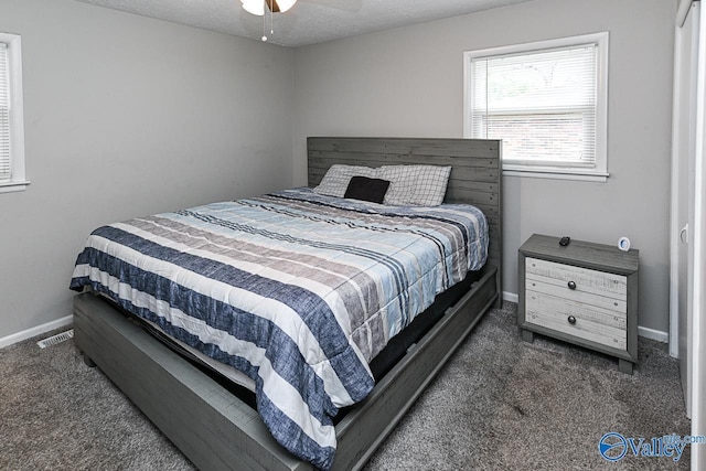 bedroom with a textured ceiling and dark colored carpet