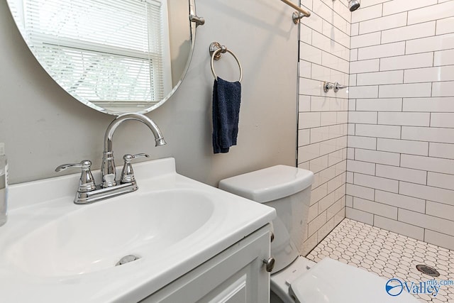 bathroom with vanity, toilet, and a tile shower