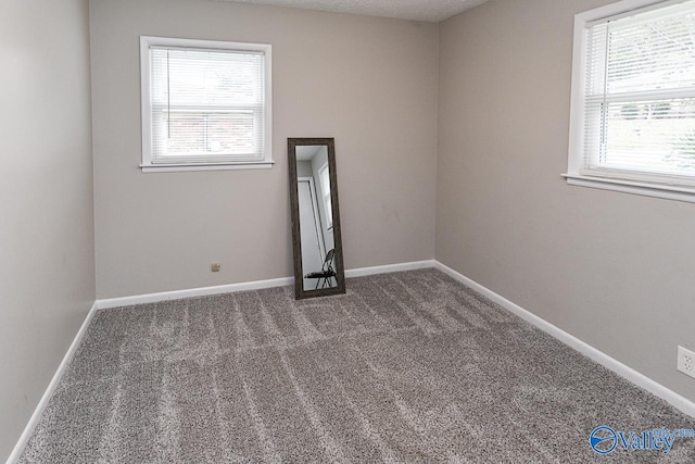 unfurnished room featuring dark carpet and plenty of natural light