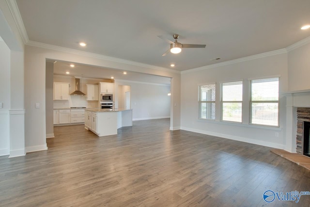 unfurnished living room with ceiling fan, ornamental molding, hardwood / wood-style flooring, and a fireplace