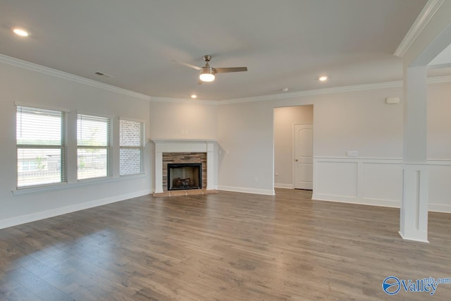 unfurnished living room with ornamental molding, hardwood / wood-style floors, ceiling fan, and a stone fireplace