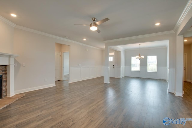 unfurnished living room featuring a fireplace, crown molding, ceiling fan with notable chandelier, and dark hardwood / wood-style floors