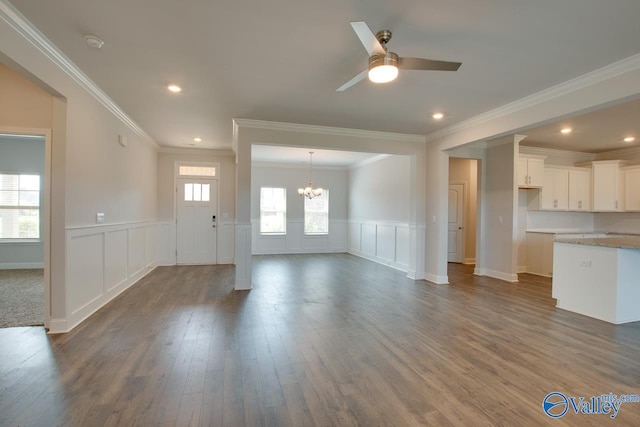 unfurnished living room featuring ceiling fan with notable chandelier, crown molding, and dark hardwood / wood-style flooring