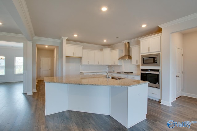 kitchen with white cabinets, stainless steel appliances, dark hardwood / wood-style floors, wall chimney exhaust hood, and a kitchen island with sink