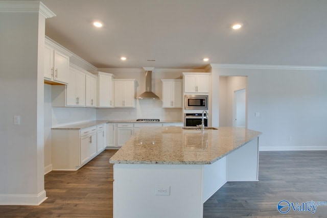 kitchen featuring white cabinets, appliances with stainless steel finishes, sink, wall chimney range hood, and an island with sink