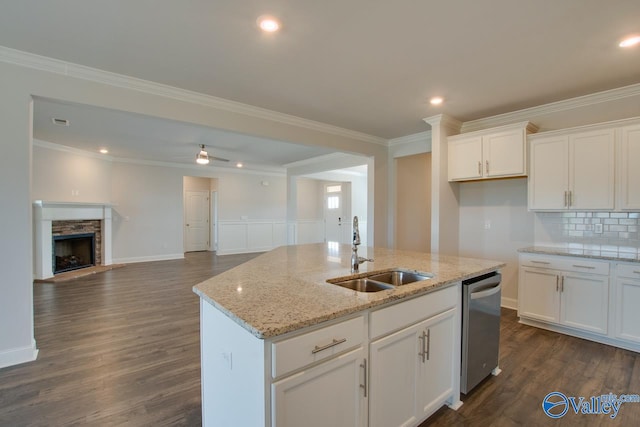 kitchen featuring a fireplace, white cabinetry, sink, and dishwasher