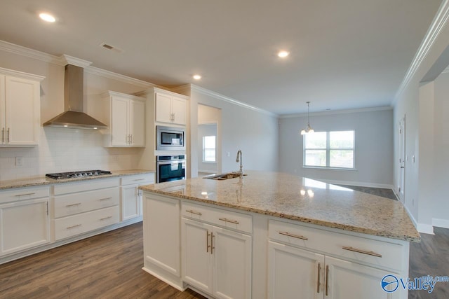 kitchen with appliances with stainless steel finishes, wall chimney exhaust hood, white cabinetry, and sink