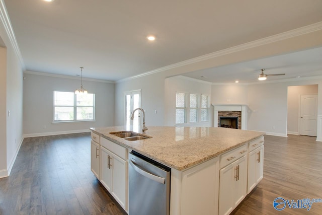 kitchen with dark hardwood / wood-style floors, a stone fireplace, an island with sink, stainless steel dishwasher, and white cabinetry