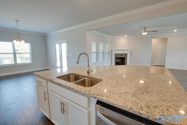 kitchen with ceiling fan with notable chandelier, light stone counters, dark hardwood / wood-style flooring, sink, and a stone fireplace