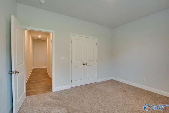 unfurnished bedroom featuring a closet and light carpet