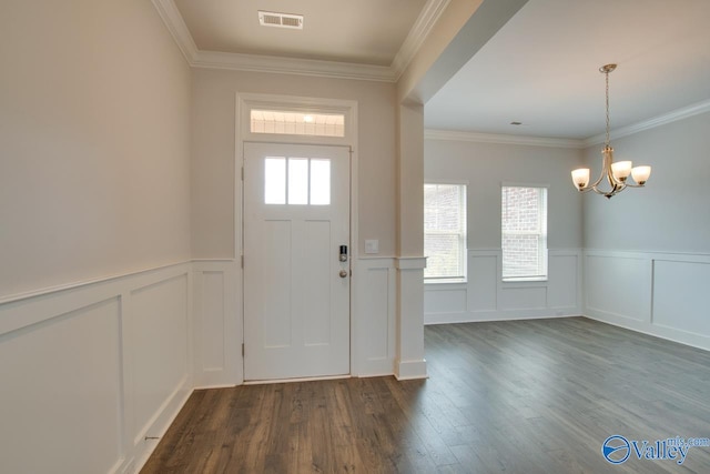 foyer entrance featuring ornamental molding, dark wood-type flooring, and a notable chandelier