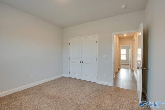 unfurnished bedroom with light colored carpet and a closet