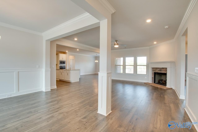 unfurnished living room featuring ceiling fan, a fireplace, ornamental molding, and light hardwood / wood-style flooring