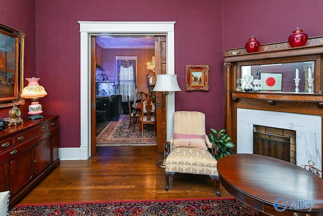 living area with dark wood finished floors, a fireplace, crown molding, and baseboards