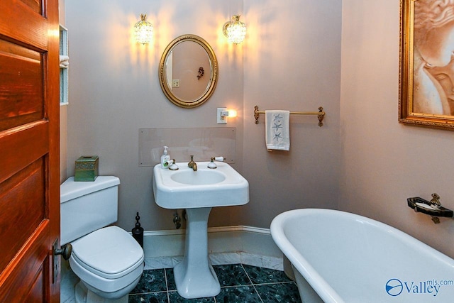 full bathroom with baseboards, a freestanding bath, and toilet