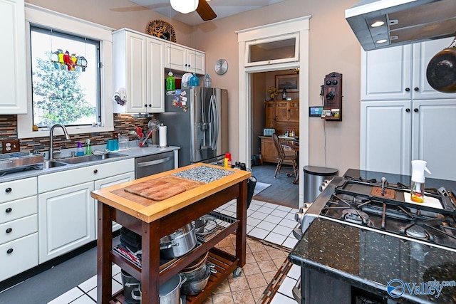 kitchen with a sink, decorative backsplash, ceiling fan, white cabinets, and stainless steel appliances