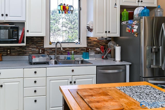 kitchen with tasteful backsplash, wooden counters, stainless steel appliances, white cabinetry, and a sink