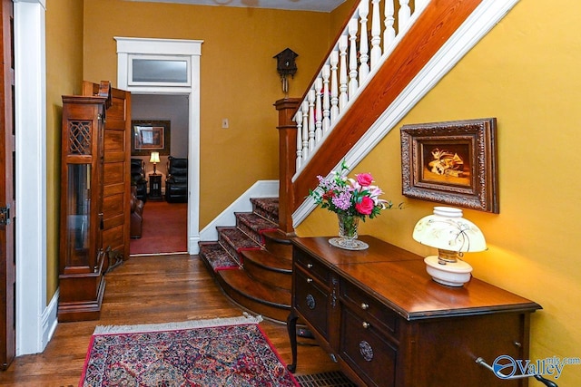 foyer entrance featuring stairway, baseboards, and dark wood-type flooring