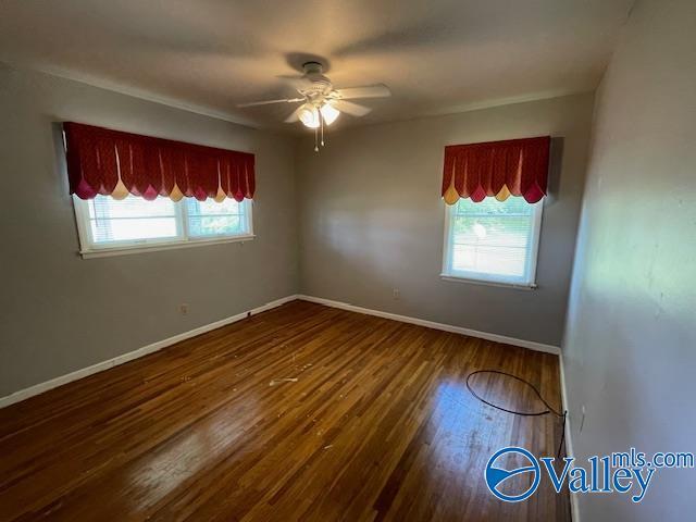 spare room with a ceiling fan, wood finished floors, and baseboards