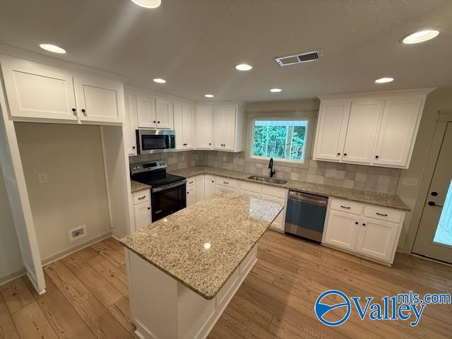 6255 Vista Trl, Southside, AL 35907 - kitchen with appliances with stainless steel finishes, a sink, white cabinets, a kitchen island, and decorative backsplash