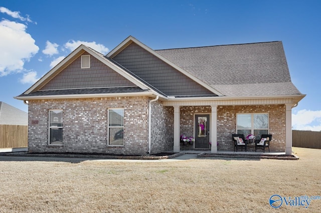 view of front of home featuring brick siding, a front yard, and fence