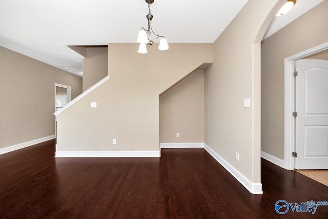 unfurnished living room featuring baseboards, an inviting chandelier, and wood finished floors