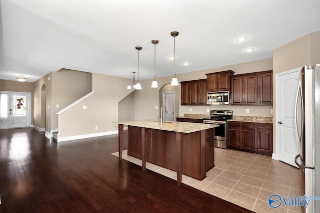 kitchen featuring stainless steel appliances, an island with sink, light wood-style floors, and a sink
