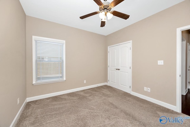 unfurnished bedroom with a closet, baseboards, carpet floors, and ceiling fan