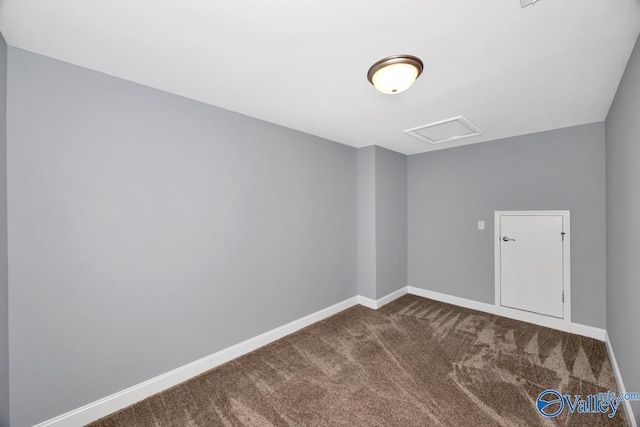 spare room featuring baseboards, attic access, and dark carpet