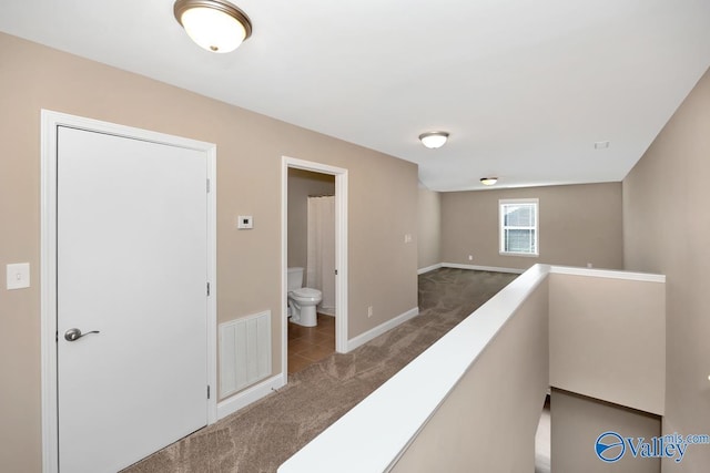 hallway with an upstairs landing, visible vents, baseboards, and carpet