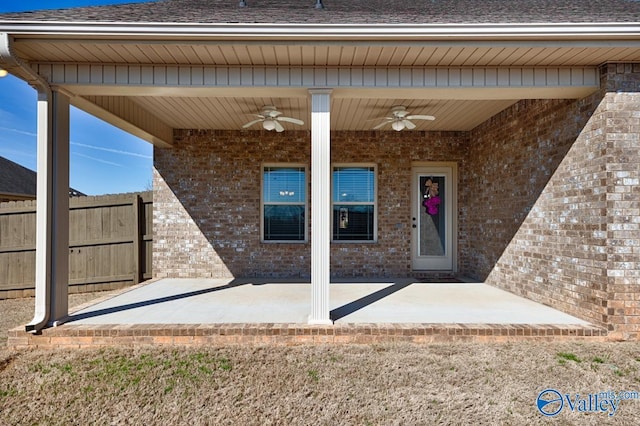 doorway to property featuring a patio, fence, brick siding, and ceiling fan