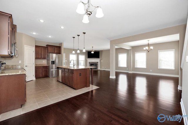 kitchen featuring a sink, light wood-style floors, appliances with stainless steel finishes, a notable chandelier, and open floor plan