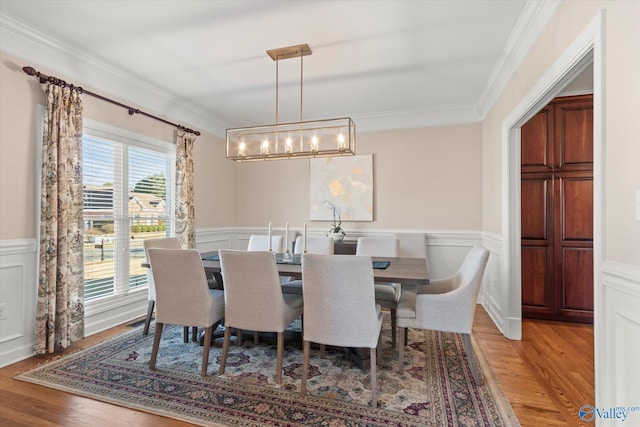 dining area with light wood-type flooring, a wainscoted wall, and ornamental molding