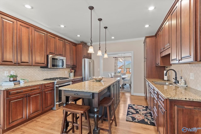 kitchen with a kitchen island, appliances with stainless steel finishes, light stone counters, decorative light fixtures, and a sink