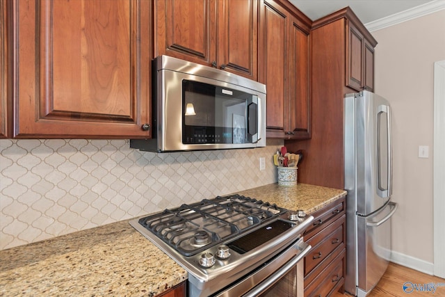 kitchen with crown molding, tasteful backsplash, appliances with stainless steel finishes, light stone countertops, and baseboards