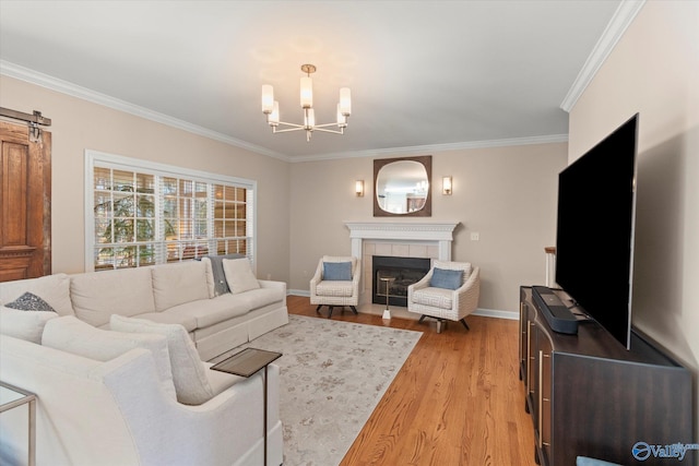 living area featuring baseboards, a tile fireplace, ornamental molding, wood finished floors, and an inviting chandelier