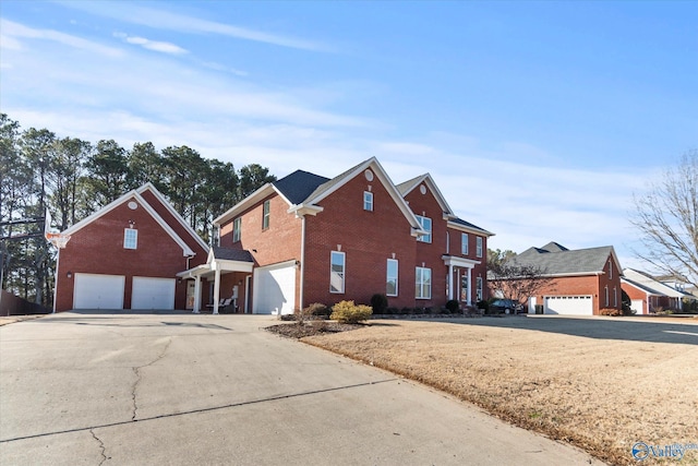 traditional home with a garage, a residential view, concrete driveway, and brick siding